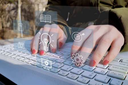 © LeoOrigami - stock.adobe.com Foto: Hände auf Tastatur mit Icons