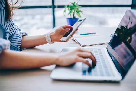 © BullRun - Adobe Stock.com Foto: Frau mit Smartphone und Laptop